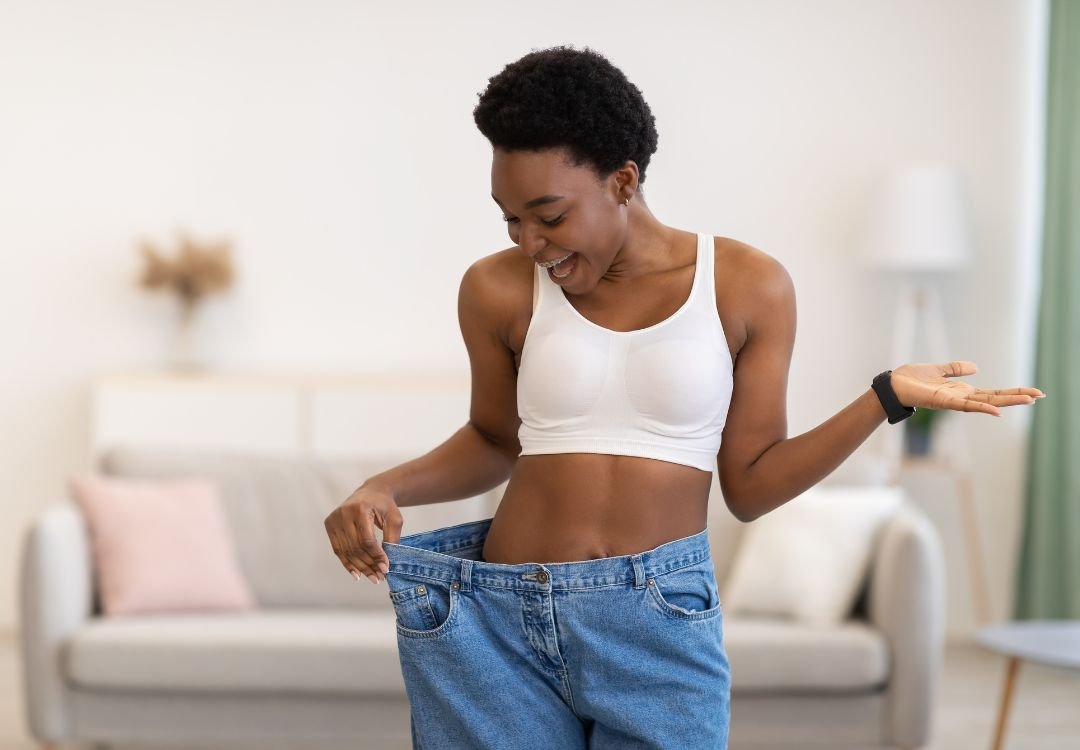 Woman showing her weight loss progress in oversized jeans